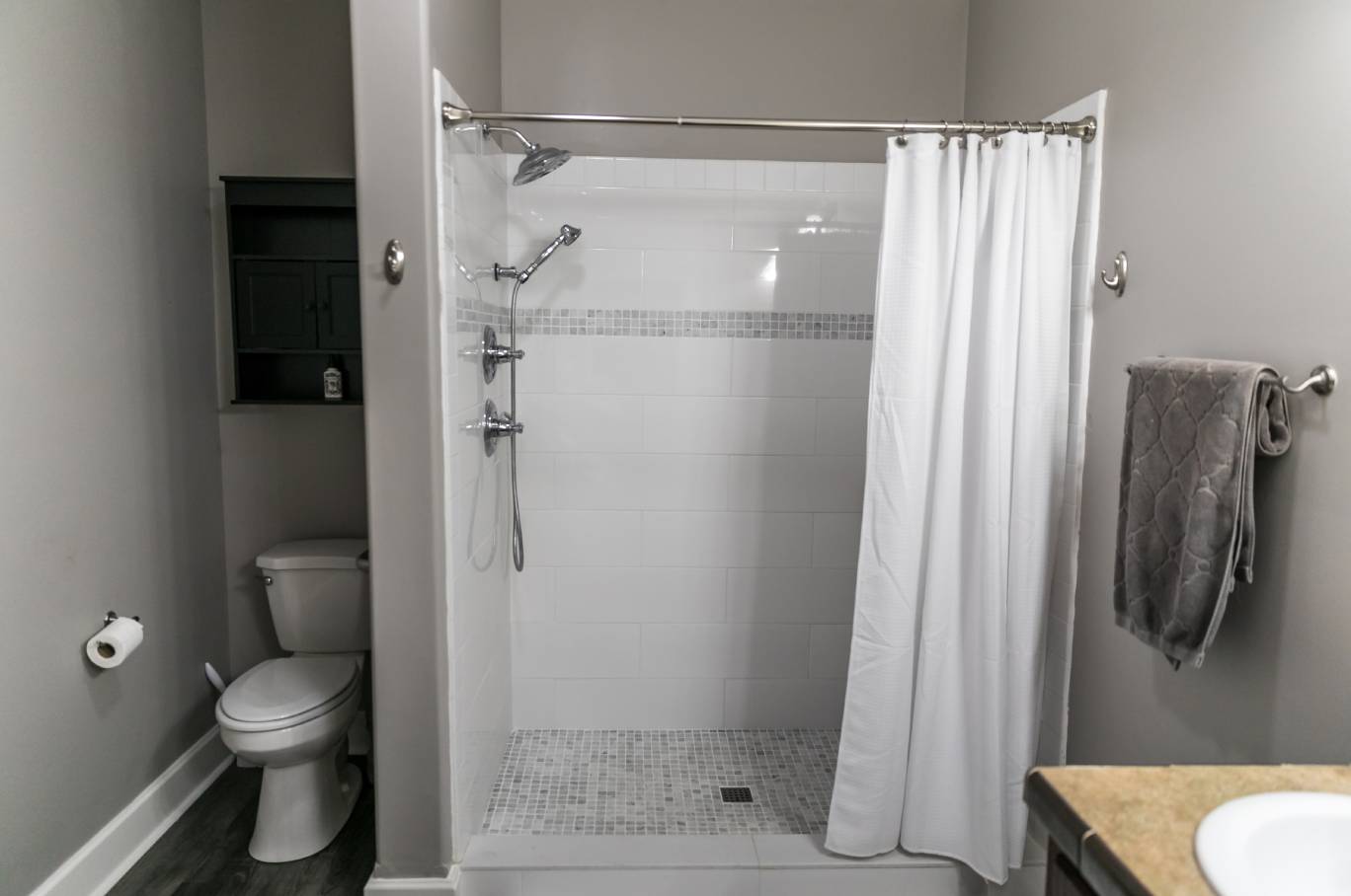A humble residential guest bathroom with a simple, modern design, bright lights, and neutral paint colors.