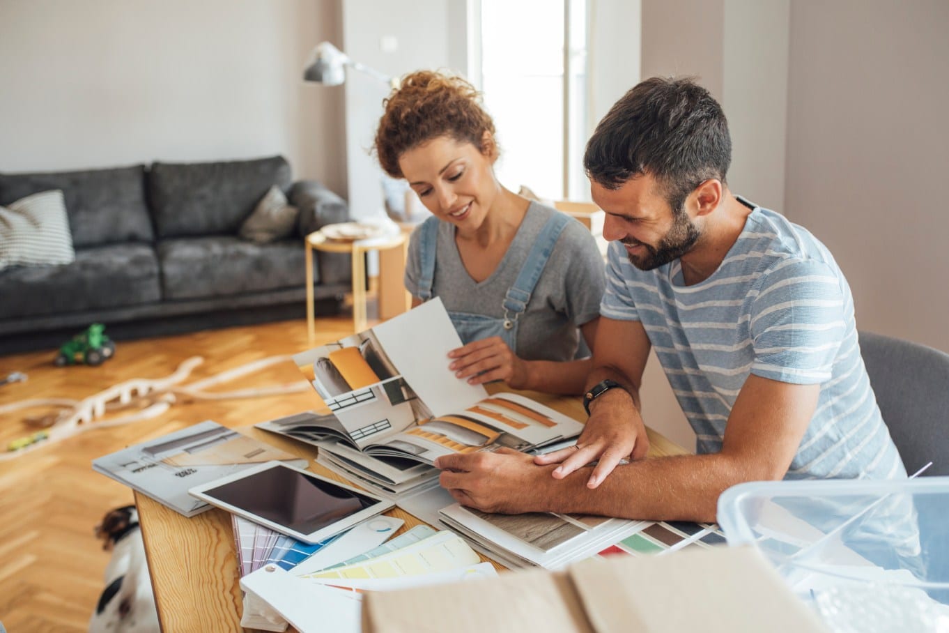 Two young homeowners discussing the best options for different home renovation projects while looking at potential designs.