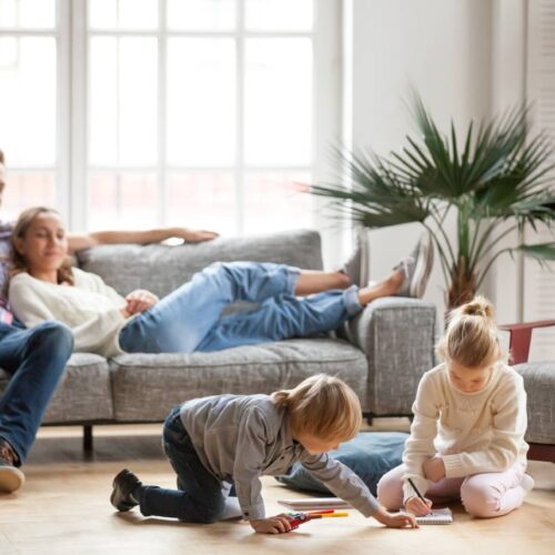 home improvement contractors A young girl and boy color together on the floor while their parents sit on the couch watching.