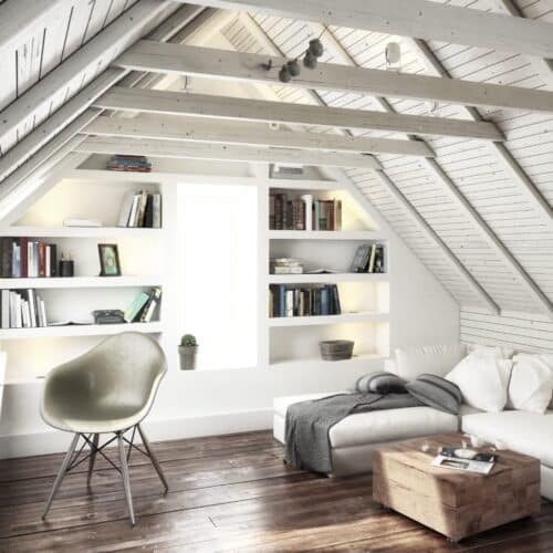 home improvement contractors A freshly renovated attic space with white features, a comfortable couch on the right, and a work desk on the left side.