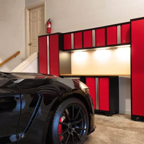home improvement contractors A nice, clean home garage with a black car parked close to the entry door. There is a red cabinet unit in front of the car.