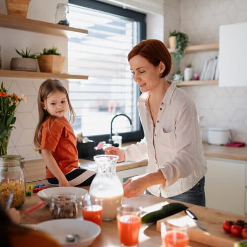 home improvement contractors A mother and her three children are preparing breakfast in the kitchen at home. The youngest is sitting on the counter.