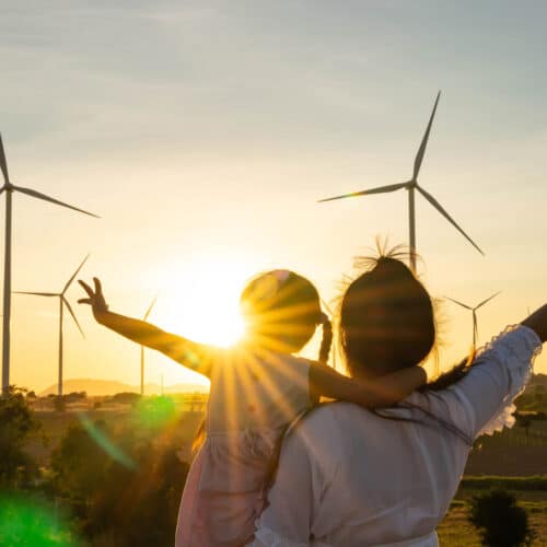 home improvement contractors A woman holding up a little girl with her arms out toward the sun in front of a field of wind turbines.