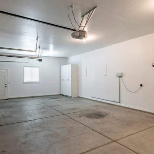 home improvement contractors An empty residential garage with an entry door leading into the home and a side door leading into the outside.