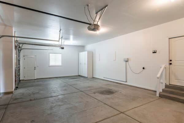 An empty residential garage with an entry door leading into the home and a side door leading into the outside.