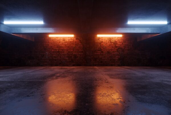 A garage with gleaming black flooring and soft, LED mood lighting that cascades on the floor and brick walls.