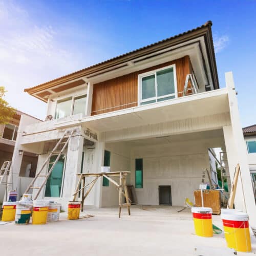 home improvement contractors Two-story home with a large open garage undergoing renovation with multiple ladders and buckets on the outside.