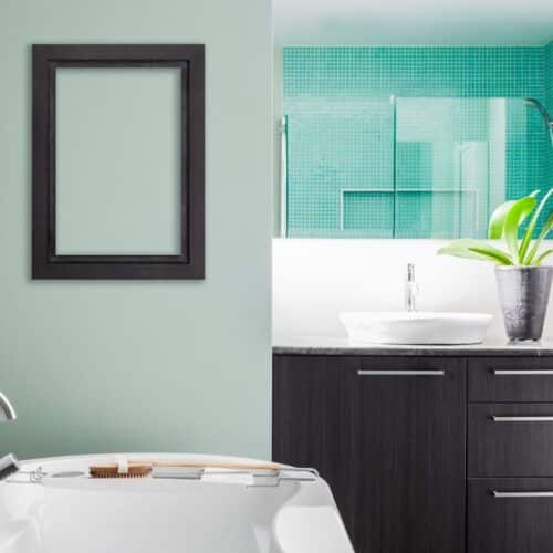 home improvement contractors A modern bathroom featuring a freestanding bathtub against a green accent wall, with an empty frame mounted on the wall.