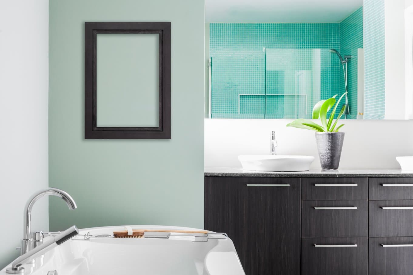 A modern bathroom featuring a freestanding bathtub against a green accent wall, with an empty frame mounted on the wall.