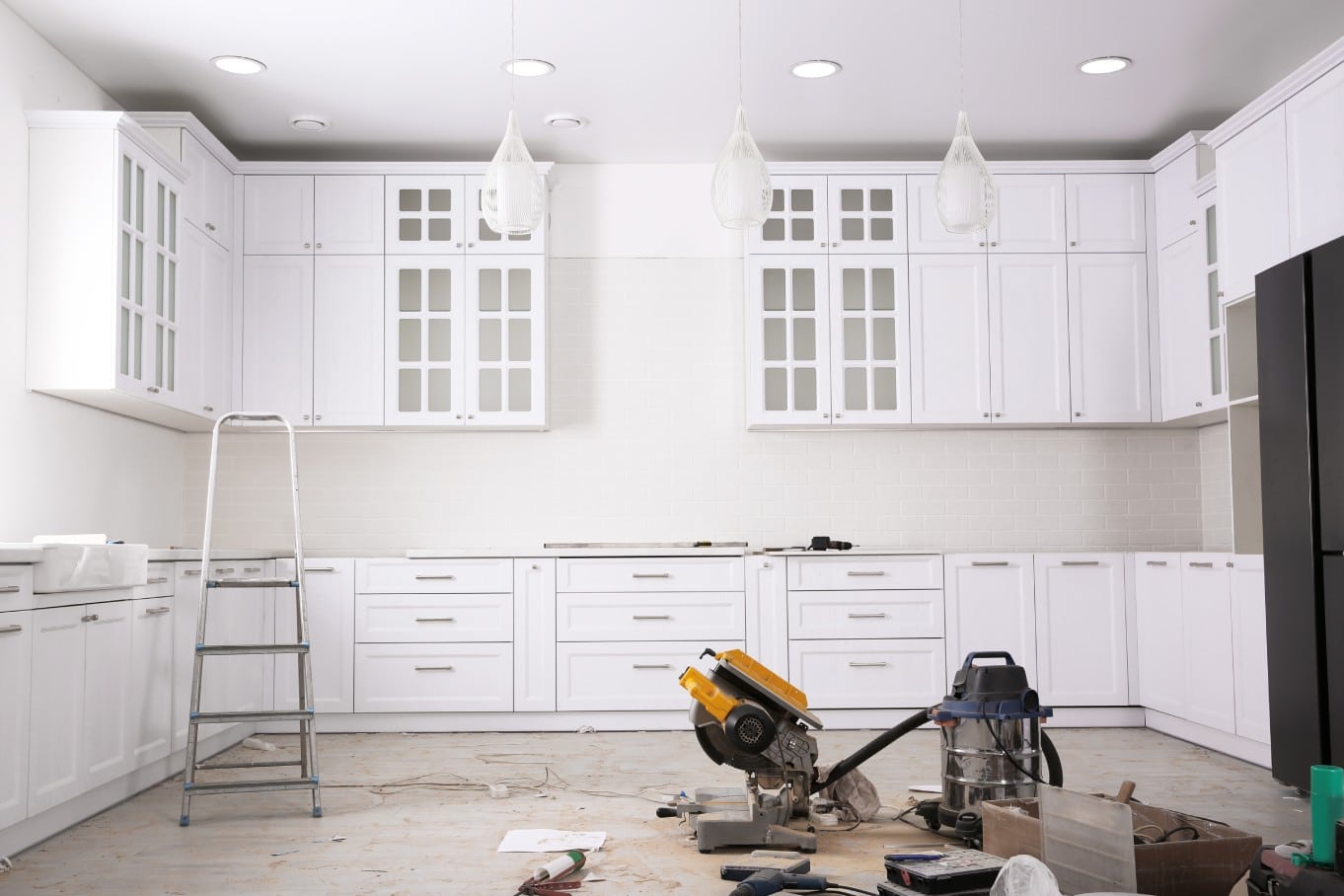 A wide view of a home's kitchen in the middle of a remodel with new cabinetry and equipment on the floor.