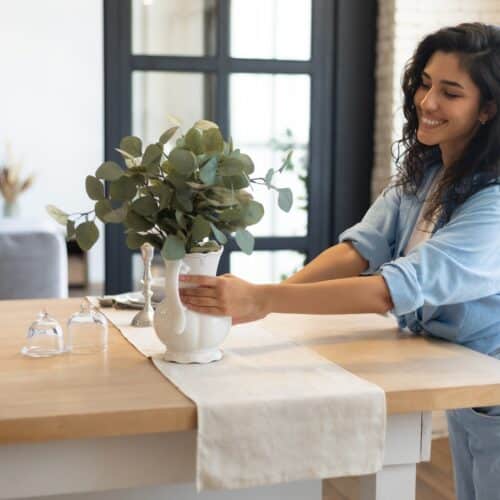 home improvement contractors A smiling woman is placing a vase on a countertop. She’s wearing a blue shirt with the sleeves rolled up.