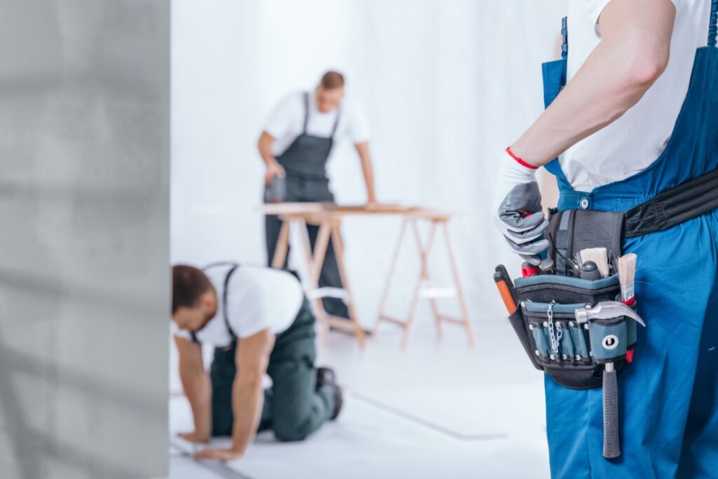Handyman wearing a tool belt, ready for home repairs and renovation work, with other skilled tradespeople.