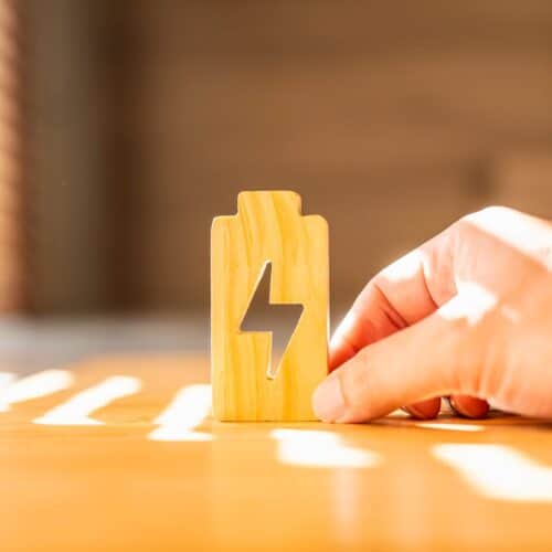 home improvement contractors A person holding a wooden block on a wooden desk inside a home office. Sunlight shines inside through a nearby window.
