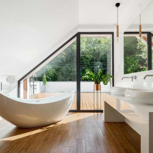 home improvement contractors An attic bathroom with a freestanding bathtub, wood floor, sloped ceiling, and large glass doors to a balcony.