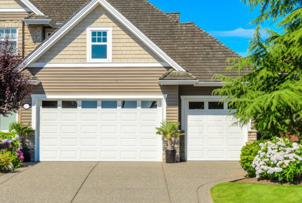 A two-story home with a three-car garage. The garage doors are white with rectangular windows on the top row of panels.