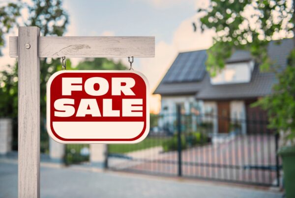 Red for sale sign displayed in front of a well-maintained residential home.