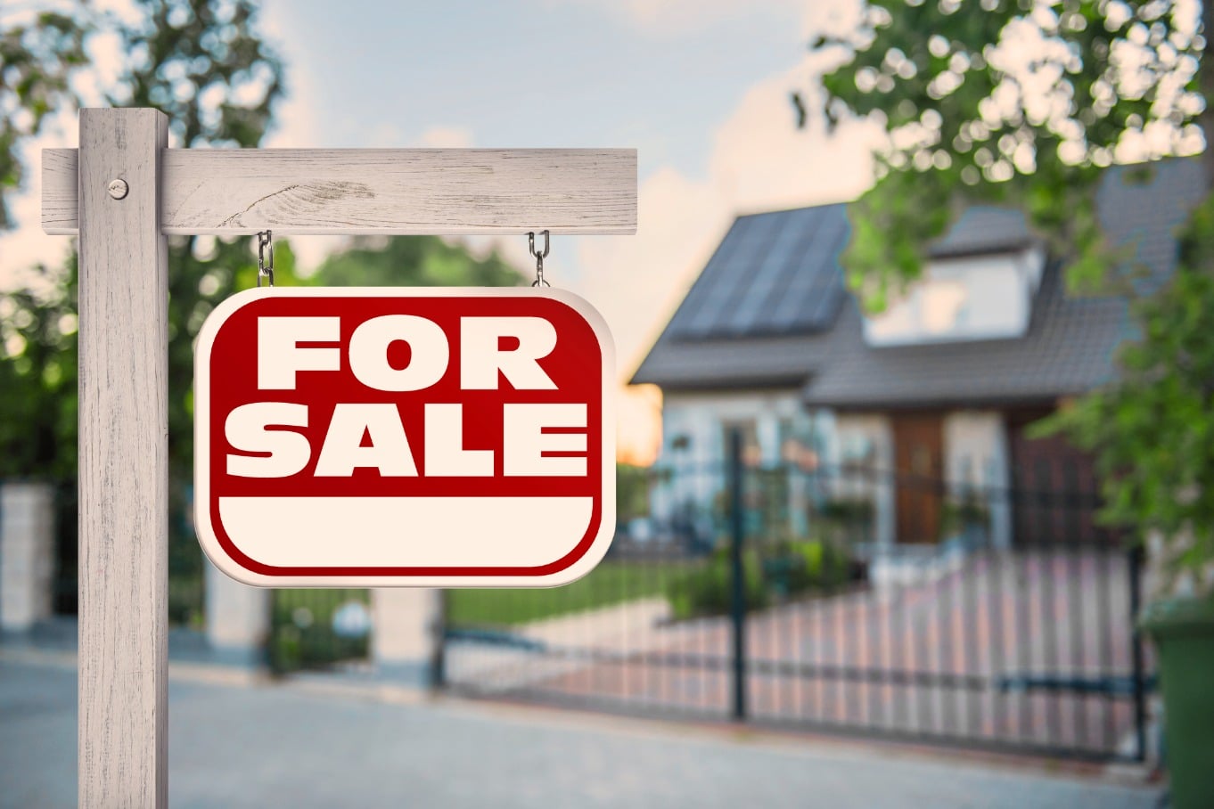Red for sale sign displayed in front of a well-maintained residential home.
